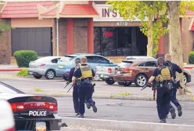  ?? ADOLPHE PIERRE-LOUIS/JOURNAL ?? Albuquerqu­e police officers run through the Lin’s Grand Buffet parking lot near Montgomery and San Mateo following a “hostage situation” at the Chinese restaurant.