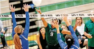  ?? [PHOTO BY SARAH PHIPPS, THE OKLAHOMAN] ?? Edmond Santa Fe’s Kaeli Robinson hits the ball as Deer Creek’s Maciee Morgan, left, and Trinity Sargent defend during Tuesday’s match won by the Wolves.