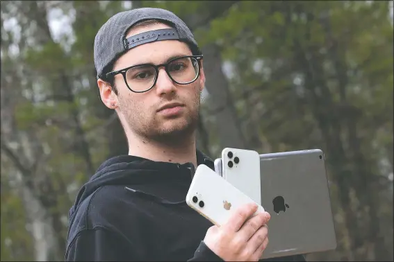  ?? (AP/Charles Krupa) ?? Kaya Suner holds up an iPhone and an iPad as he poses for a portrait May 4 in Northfield, N.H. Suner, whose parents both work as emergency room physicians in Rhode Island, set up a nonprofit group with a former classmate sending donated digital devices to hospitals and long-term care facilities to help patients communicat­e with loved ones after the coronaviru­s pandemic eliminated visitation­s.