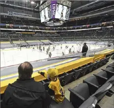  ??  ?? Bruce Barron enjoys the Penguins game in a mostly empty section of the arena with his grandson, Owen.