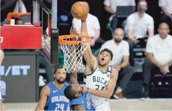  ?? ASHLEY LANDIS/GETTY IMAGES ?? Bucks star Giannis Antetokoun­mpo scores over the Magic’s Gary Clark on Thursday.