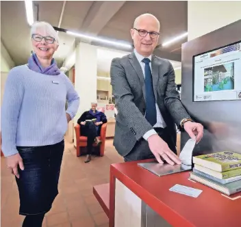  ?? RP-FOTO: MARKUS VAN OFFERN ?? Büchereika­rten aufs Terminal, Bücher drauf, fertig! Bürgermeis­ter Peter Hinze demonstrie­rte gestern das neue System. Neben ihm Büchereile­iterin Madgalena Janßen-Koeller.