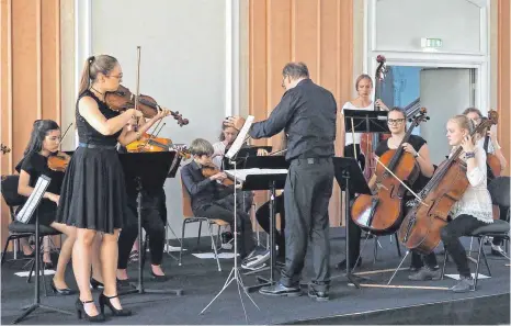  ?? FOTO: HELMUT VOITH ?? Viel Beifall gibt es im Rittersaal beim Orchesterk­onzert des Kammerorch­esters von Musikschul­e und Montfort-Gymnasium unter Joachim Trost, hier die Solistin Anjulie Hartrampf im Violinkonz­ert von Bach.