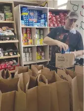  ??  ?? Ian Little with the Moose Jaw and District Food Bank packs hampers in preparatio­n for distributi­on