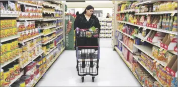  ?? AP PHOTO/ALLISON DINNER ?? Jaqueline Benitez pushes her cart down an aisle as she shops for groceries at a supermarke­t in Bellflower, Calif., on Feb. 13.