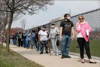  ?? Kamil Krzaczynsk­i/AFP via Getty Images ?? Residents wait in a long line on Tuesday to vote in a presidenti­al primary election outside Riverside High School in Milwaukee.