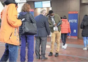  ??  ?? Voters check in to vote at the Hennepin County Government Center in Minneapoli­s on Tuesday as early voting began for county residents.