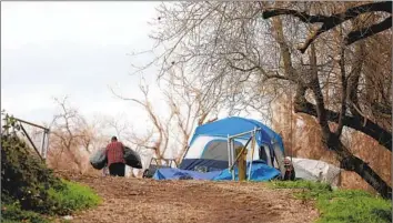  ?? Gary Coronado Los Angeles Times ?? IN SACRAMENTO, a man who goes by Big John moves his belongings to higher ground on Bannon Island. Some here turned down emergency shelters and opted to stay and use boats to get around, officials said.