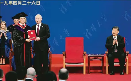  ?? FOTO ČTK/AP ?? Doktorát pro Putina. Ruský prezident převzal v Pekingu čestný doktorát univerzity Čching-chua. Vpravo vsedě tleská jeho čínský protějšek Si Ťin-pching.