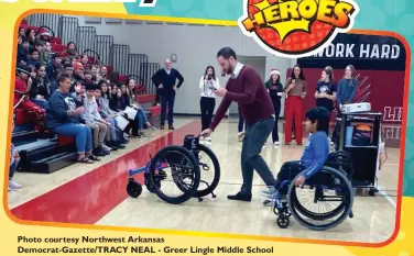  ?? Photo courtesy Northwest Arkansas Democrat-Gazette/TRACY NEAL ?? - Greer Lingle Middle School
Principal Chip Greenwell pushes Angel Flores’ new all terrain wheelchair to his family at an assembly Tuesday Dec. 20, 2022 at the school in Rogers.