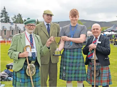  ?? ?? Inaugural honour Andrew Murphie receives the Junior Heavyweigh­t Championsh­ip trophy from honorary president David Mclaren. Also pictured are chieftain Andrew Jardine Paterson, second left, and Games committee president Stuart Laing. Inset left, more than 100 dancers took part