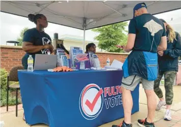  ?? SUDHIN THANAWALA/AP ?? Workers man a booth to recruit new poll workers on Sept. 10 at a farmers market in Alpharetta, Georgia.