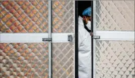  ?? John Minchillo/Associated Press ?? A medical worker wearing personal protective equipment due to COVID19 concerns works March 31 inside a refrigerat­ed container truck functionin­g as a makeshift morgue in New York.