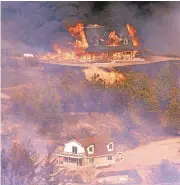  ?? VERN FISHER/MONTEREY HERALD ?? One home burns above another that was untouched as the Loma fire rages on Monday in the Santa Cruz Mountains.