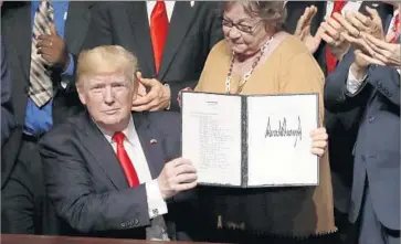  ?? Joe Raedle Getty Images ?? PRESIDENT TRUMP displays the order for policy changes on Cuba at the Manuel Artime Theater in Miami’s Little Havana. A majority of Cuban Americans oppose the U.S. embargo on the island, a study says.