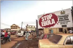  ??  ?? In this Jan. 15, 2016 file photo, people pass a banner reading ‘STOP EBOLA’ forming part of Sierra Leone’s Ebola free campaign in the city of Freetown, Sierra Leone. Fraud by Red Cross workers and others wasted more than $6 million meant to fight the...