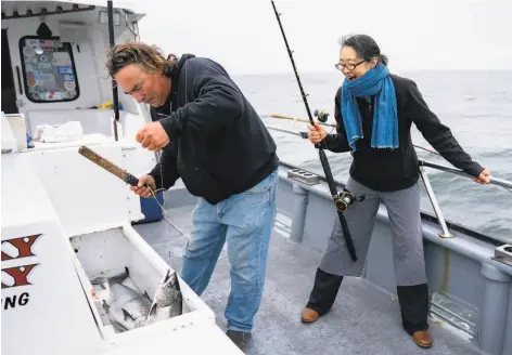  ?? Photos by Santiago Mejia / The Chronicle 2018 ?? John Dresser subdues a Chinook salmon after Mariko Grady reeled the fish into the Wacky Jacky fishing boat off the coast of San Francisco. The marine forecast is calling for warmer temperatur­es and calmer seas this weekend, welcome news for fishermen.