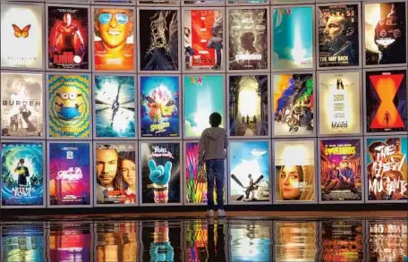  ?? Jay L. Clendenin Los Angeles Times ?? A CHILD looks at movie posters in the lobby of ArcLight Cinemas in El Segundo in March 2020, before the pandemic-related closures.