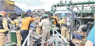  ??  ?? Rescue members search for victims after the explosion at an STX Offshore and Shipbuildi­ng plant. — AFP photo