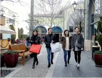  ?? — Reuters ?? Tourists hold shopping bags as they walk along the Las Rozas Village mall in Las Rozas, Spain. Regional government­s, constructi­on and travel firms as well as shops are working hand-inhand to recast Spain — and Madrid in particular — as a retail hub to...