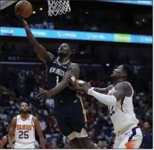  ?? (AP/Gerald Herbert) ?? New Orleans forward Zion Williamson (1) goes to the basket Sunday past Phoenix center Deandre Ayton (right) during the second half of the Pelicans’ 129-124 victory over the Suns in New Orleans. Williamson scored a game-high 35 points in the victory for the Pelicans, who now stand atop the NBA’s Western Conference standings on the strength of a seven-game winning streak.