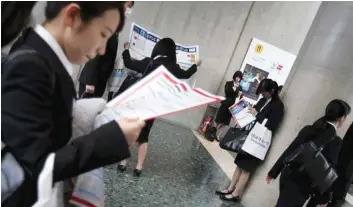  ?? — Reuters ?? Female job-seekers look at maps of a job fair held for fresh graduates in Tokyo.