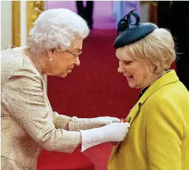  ??  ?? TAKING NO CHANCES: The Queen wears gloves as she pins a CBE medal on to the jacket lapel of actress Wendy Craig last week