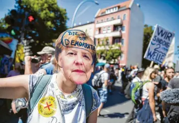  ?? Foto: Christoph Soeder, dpa ?? Eine Frau trägt bei der Demonstrat­ion in Berlin eine Merkel-maske mit der Aufschrift „Bye bye Demokratie“. Andere kamen zum Protestzug mit Schildern wie „Wir sind die 2. Welle“.