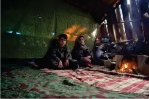  ??  ?? Two sib l ings be l onging to the Gujjar community inside a makeshift hut made of mud and wooden l ogs (Zafar Dar)