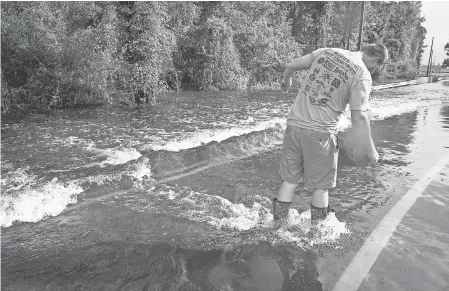  ?? JACK GRUBER/USA TODAY ?? Lee Duncan of Clarkton, N.C., inland from Wilmington, checks the road on foot, finding it unfit to drive through with his truck. Duncan was unable to find a way home because of flooded roads across Slades Swamp.