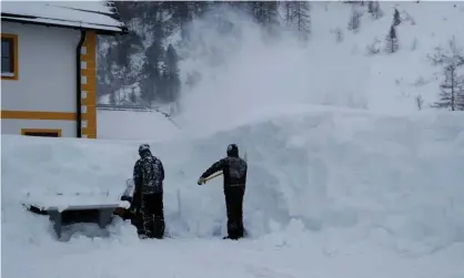  ?? Photograph: Leonhard Föger/Reuters ?? Two workers remove snow after a blizzard in the Austrian Alpine ski resort of Obertauern.