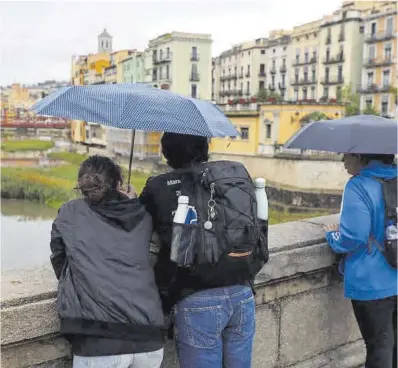  ?? David Aparicio ?? Diverses persones observen sota la pluja el riu Onyar al seu pas per Girona, ahir.