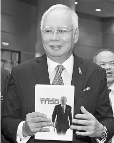  ?? - Bernama photo ?? Najib showing the book on TN50 philosophi­es after addressing civil servants at the 15th Civil Service Premier Assembly in Putrajaya.