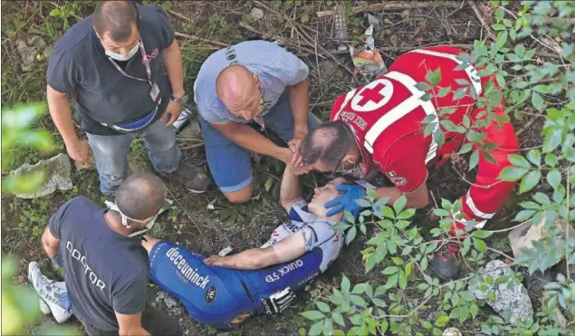  ??  ?? Los servicios de rescate y sanitarios atienden a Remco Evenepoel, que cayó por un puente desde unos cinco metros de altura tras colisionar con un muro de piedra.