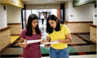  ?? TAMIR KALIFA / AMERICAN-STATESMAN ?? Lake Travis High School students Francisca Morales (left) and Laura Jimenez, both 16, check class schedules at a back-to-school event Aug. 3. Lake Travis district classes start Wednesday.