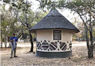  ?? Washington Post photo by Andrea Sachs ?? ■ Shaun Thompson of Texas stands outside a Ndebele village hut, a lodging upgrade at Big Cave Camp near Matobo National Park in Zimbabwe. Most in Thompson’s group chose to pitch a tent.