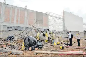  ??  ?? Bomberos voluntario­s revisan los escombros que cayeron sobre el andamio en la obra.