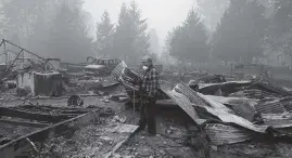  ?? JOHN LOCHER AP ?? George Coble walks through what remains of a home on his property destroyed by a wildfire Saturday in Mill City, Oregon.