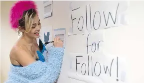  ??  ?? Miley Cyrus signs a wall in a dorm while campaignin­g for Hillary Clinton at George Mason University in Virginia.