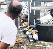  ??  ?? Mark Ward surveys the destructio­n of his neighbour’s mobile home in Bay County, Florida. Ward and his neighbours say that the rural parts of the county have seen little help since Hurricane Michael.