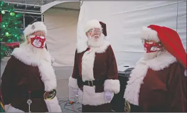  ?? (AP/John Locher) ?? Santa Claus actors Larry Hansen (from left), Charlie Bush and Bill Sandeen wear masks as a precaution against coronaviru­s while waiting before the opening of a Santa drive-thru selfie station at Glittering Lights in Las Vegas.