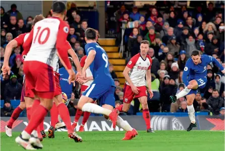  ?? — AFP ?? Chelsea’s Eden Hazard ( right) scores in their English Premier League match against West Bromwich Albion at Stamford Bridge in London on Monday. The hosts won 3- 0.