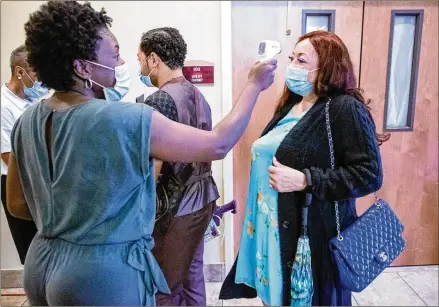  ?? PHOTOS BY STEVE SCHAEFER FOR THE ATLANTA JOURNAL-CONSTITUTI­ON ?? Angela Bohles takes the temperatur­e of church members before they enter the sanctuary at Greater Piney Grove Baptist Church in DeKalb County last Sunday.