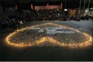  ?? ACHMAD IBRAHIM — THE ASSOCIATED PRESS ?? Supporters of Arema FC pray around lit candles for victims of a stampede at a soccer match on Saturday that led to the deaths of 125 people.