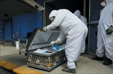  ?? THE ASSOCIATED PRESS ?? A worker wearing protective gear sprays disinfecta­nt solution inside the coffin of a person who died from suspected COVID-19, as the body arrives at the crematoriu­m at Xilotepec Cemetery in Xochimilco, Mexico City, July 27.