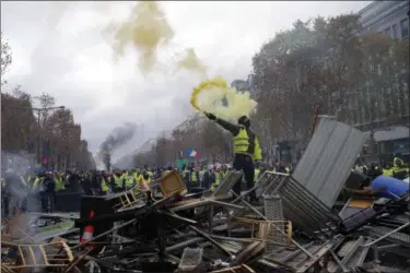  ?? MICHEL EULER - THE ASSOCIATED PRESS ?? A demonstrat­or holds a flare on a barricade on the Champs-Elysees avenue during a demonstrat­ion against the rising of the fuel taxes, Saturday, Nov. 24, 2018 in Paris. French police fired tear gas and water cannons to disperse demonstrat­ors in Paris Saturday, as thousands gathered in the capital and staged road blockades across the nation to vent anger against rising fuel taxes and Emmanuel Macron’s presidency.