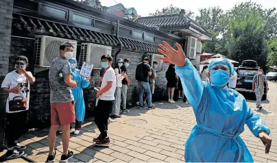  ?? [ Reuters ] ?? Vor dem abgesperrt­en Xinfadi-Markt in Peking gestikulie­rt eine aufgeregte Krankensch­wester im Schutzanzu­g.