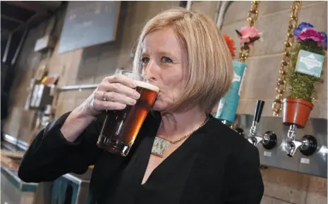  ?? CP FILE PHOTO ?? Alberta Premier Rachel Notley drinks a beer while touring the Cold Garden Beverage Company in Calgary on March 27, 2017. The Alberta government is retreating on craft beer subsidies after they were ruled unconstitu­tional but will open a new front by targeting the province of Ontario for what it says are its unfair trade barriers.
