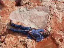  ?? (Reuters) ?? ABORIGINAL ELDER Richard Hunter lies alongside a 1.75-meter sauropod dinosaur track in Western Australia on Sunday.