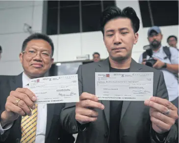  ?? VARUTH HIRUNYATHE­B ?? TV host Kanchai Kamnerdplo­y, right, and lawyer Decha Kittiwitth­ayanan show cheques worth 41.75 million baht submitted on behalf of the family of Orachon ‘Praewa’ Devahastin na Ayudhya to the Civil Court yesterday.